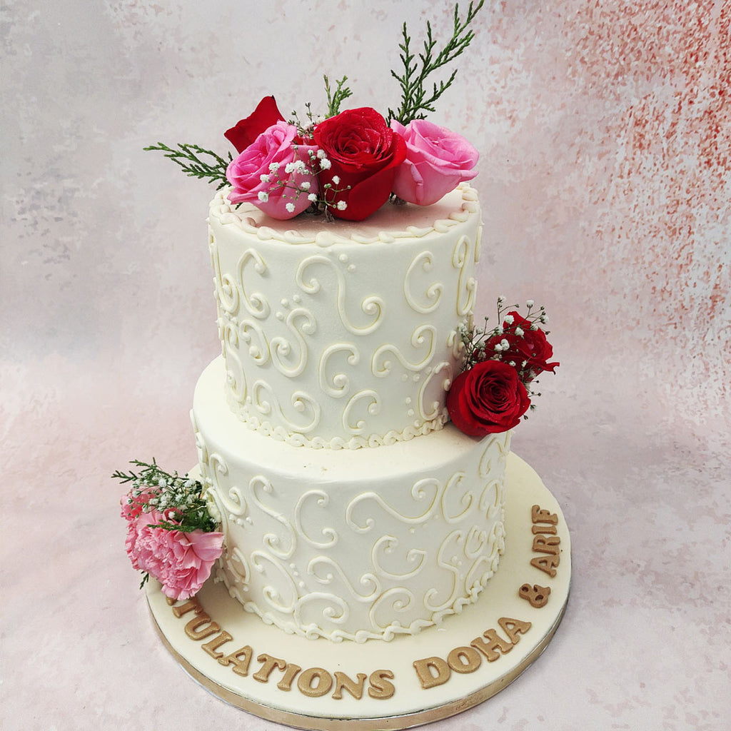 Everything about this design makes this floral engagement cake a romantic cake, from the two tiers of one cake symbolising two hearts coming together as one, to the intricate lacey white buttercream patterns coating both tiers.