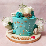 This blue floral cake with macarons features the inclusion of white and gold macarons, strategically placed to provide a delightful crunch, embodying the sweet whispers of devotion.