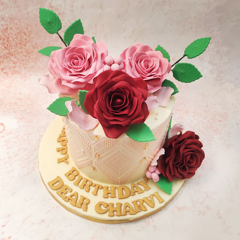 Adorning the top of this Floral Theme Cake are beautifully crafted fondant roses in shades of pink and deep red, each petal meticulously detailed to mirror the beauty of real flowers. 