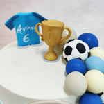 Perched on top of this Football Fault Line Cake is a miniature golden trophy, a symbol of triumph, and a football jersey, representing the young athlete’s dreams and dedication to the sport. 