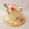 This cream-colored flower vase cake comes adorned with abstract gold ornamentation and fresh flowers delicately embedded into its top, resembling a magnificent flower vase. 