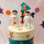 The showstopper is the space theme cake topper: which is that of the two astronauts standing on top, like this  two tier astronaut theme cake is the moon, planting a flag into it with a rocket in the background.