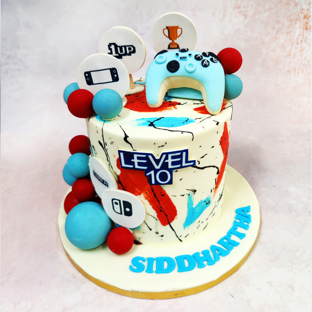 This exhilarating Game Controller Cake features bold splashes of red and blue marble across the creamy backdrop echo the vibrant visuals of arcade battles and late-night co-op sessions. 