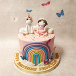 Atop this pink girl and unicorn rainbow cake sits a charming figurine of a girl and her faithful unicorn companion, symbolising the magical bond between dreams and reality.