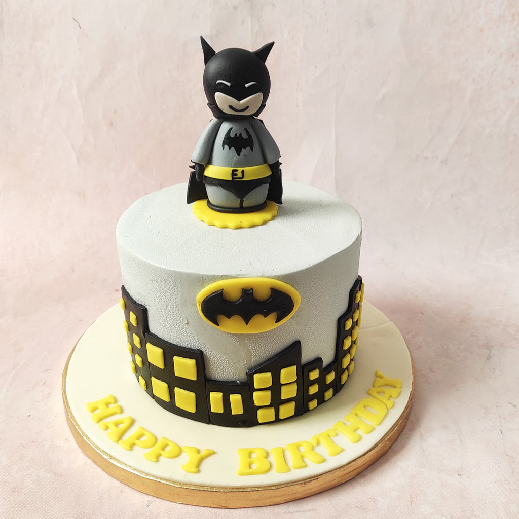 The grey base of this Batman Cake sets the eerie tone, while black and yellow buildings sprawl along the bottom, reminiscent of the brooding cityscape Batman tirelessly protects.