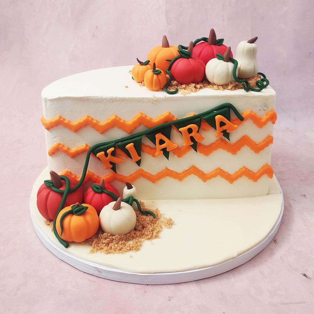 The white base, adorned with a whimsical orange zigzag, sets the stage for a slice of this Pumpkin Cake Design masterpiece.
