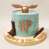On either side of the blue Harry Potter Snitch cake, you will find a delectable chocolate wand and scroll. 