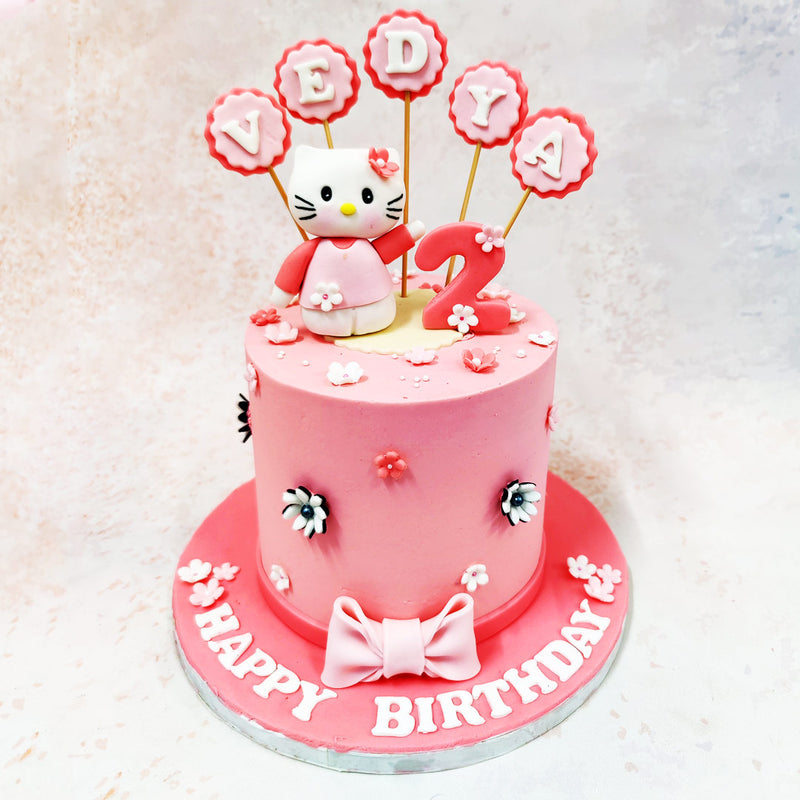 At the heart of this Hello Kitty Theme Cake is a charming edible model of Hello Kitty herself, dressed in a sweet pink outfit with a delicate flower on her ear, radiating charm and innocence. 