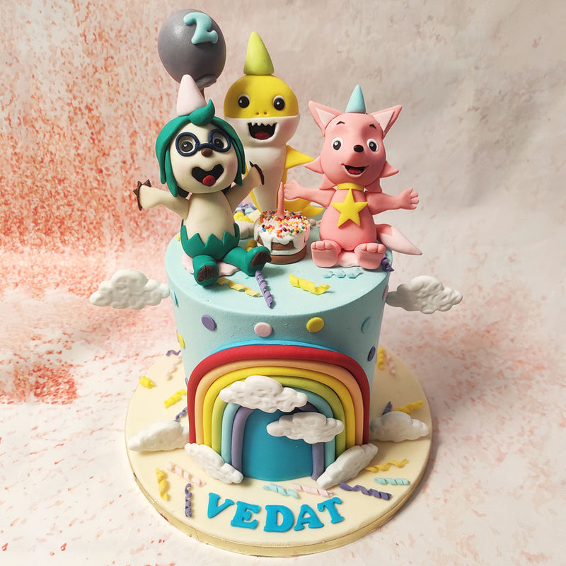 This Cartoon Theme Cake features vibrant shades of blue with a beautiful rainbow at the centre and a miniature birthday cake on top.