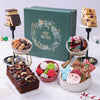 Assorted Christmas treats including cookies, macarons, and a cake in front of a 'Merry Christmas' gift box.