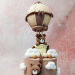 The real showstopper is the teddy bear hot air balloon cake topper: a realistic white and brown hot air balloon with a teddy bear in the basket. 