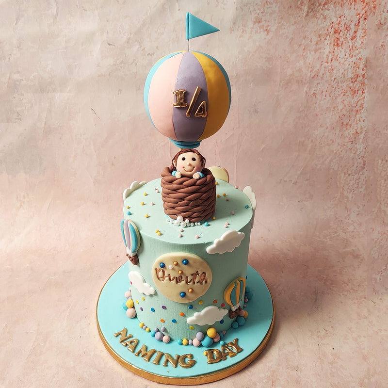 Atop this Aviation Cake, a vibrant hot air balloon takes centre stage, inside, a figurine of a little boy peeps out with pure delight