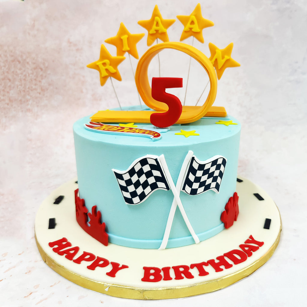 The sleek light blue backdrop of this Toy Car Cake serves as the perfect racing sky, complemented by the signature Hot Wheels racing track design suggested by the golden ring topper