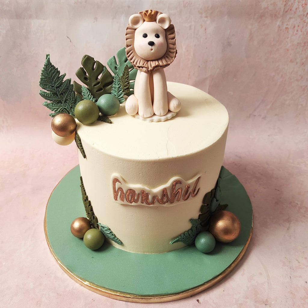 The base of this Lion Design Cake, adorned in lush greenery, is a canvas for a lion-themed masterpiece.