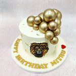 Resting atop this Lion Birthday Cake are a cluster of metallic gold spheres, cascading gracefully down the side, adding a sense of elegance and grandeur. 
