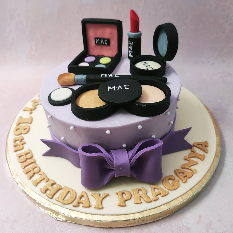 In line with the aesthetic of a gift box, spot the contents of the box that the base of this makeup set cake resembles strewn on top. 