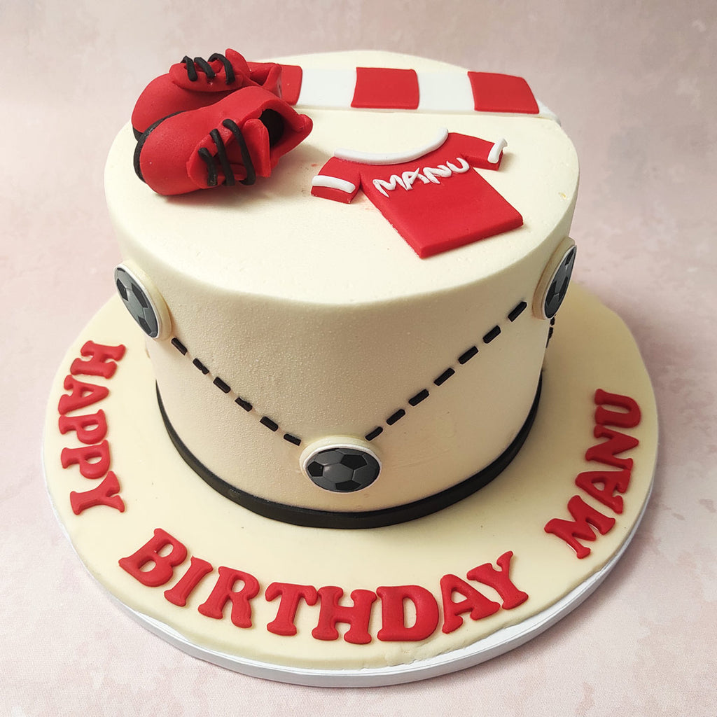 Football enthusiasts will revel in the zigzag pattern of black and white footballs that circumnavigate this Man Utd Cake, echoing the excitement of a match in full swing. 