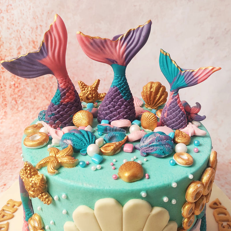 Scattered across the ocean-blue icing on this Mermaid Theme Birthday Cake are delicate seashells, starfish, and pearls, each meticulously crafted to add an authentic touch of marine magic.