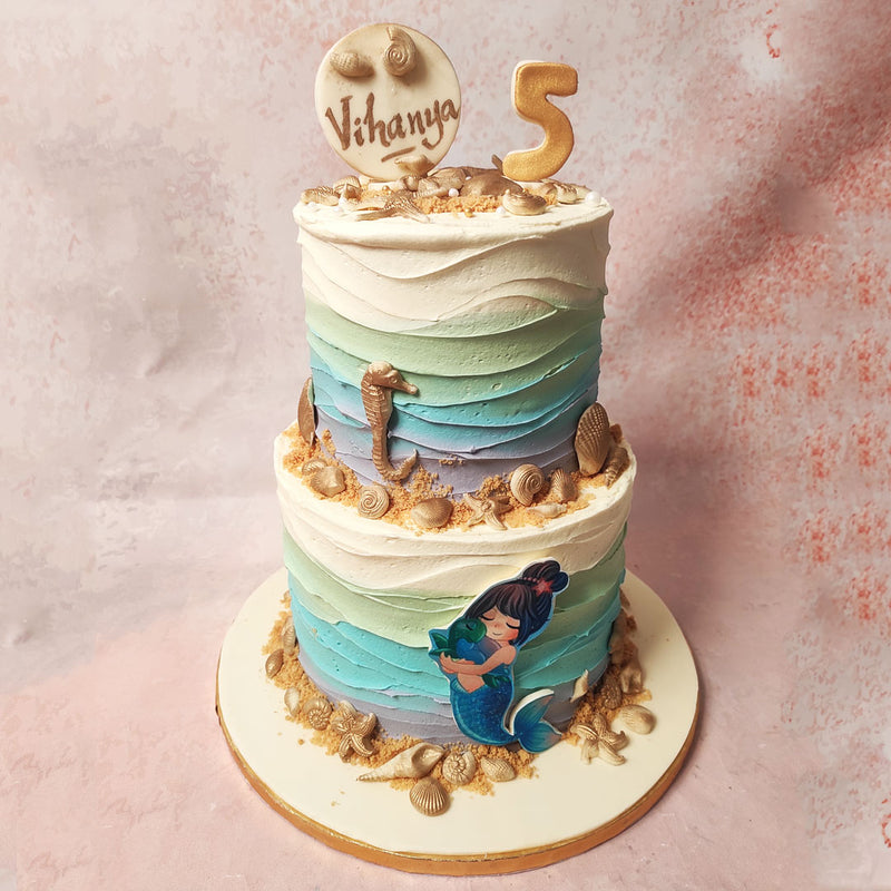 The centrepiece of this 2 Tier Beach Cake, however, is a beautifully crafted mermaid embracing a sea turtle—a heartwarming symbol of friendship and guidance through life’s vast oceans.