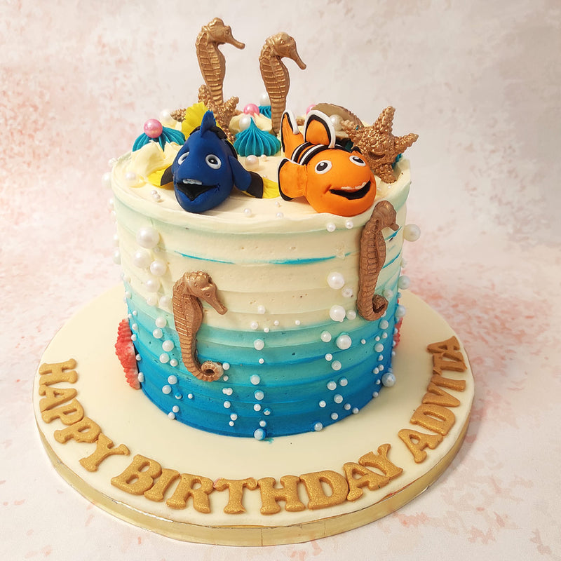 The design of this Nemo Dory Cake features a mesmerising blue-to-white ombre design that mirrors the gentle transition of the ocean depths, drawing you into its magical world. 