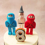 Dominating the centre stage of this Ninjago Cake is Sensei Wu, a masterful 3D figurine crafted from edible delight, flanked by his valiant disciples, the four ninjas of legend.