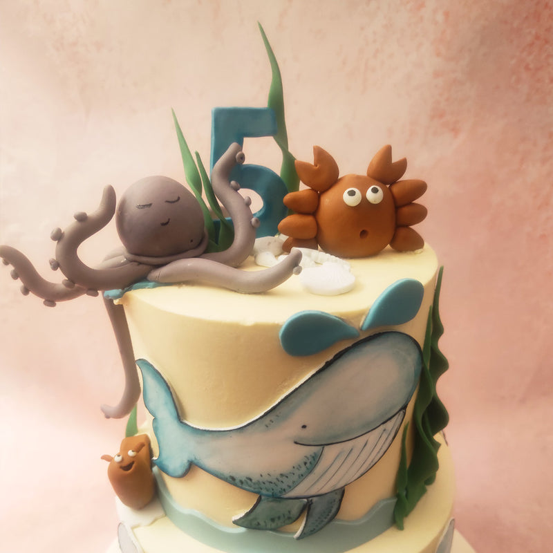 Playful whales gracefully glide through the water, their tails splashing joyfully. Adorable octopuses extend their tentacles in a friendly greeting, while mischievous crabs scuttle along the ocean floor created on this octopus cake. 