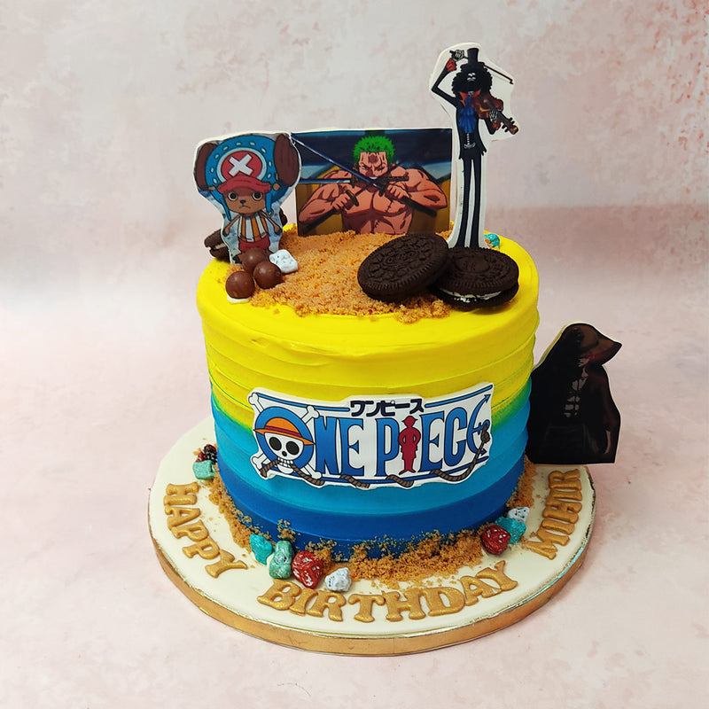 A bright blue to yellow, textured and thick layered or velvety buttercream coats the base of this One Piece birthday cake for kids with the logo of the show at the centre.