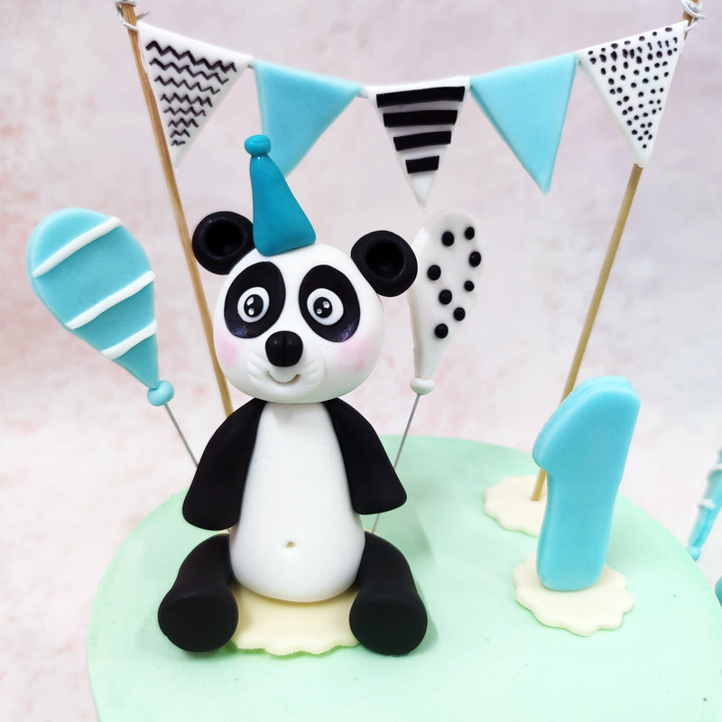 The star of this Panda Birthday Cake For Kids is a pair of adorable fondant pandas - one perched atop the design wearing a turquoise party hat beneath a festive bunting banner.