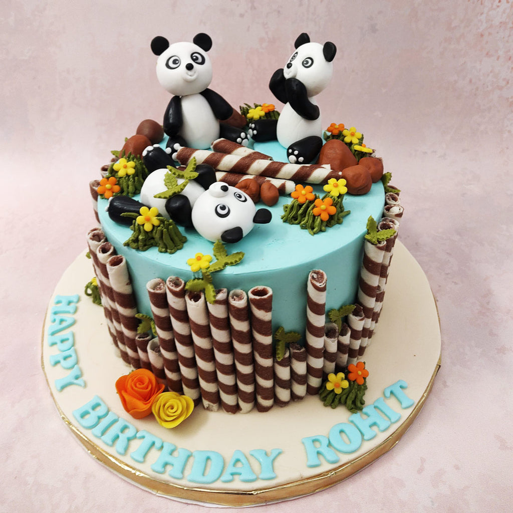 Featuring a sky blue base, this panda birthday cake for kids is ornamented with chocolate twisters all around the borders and the top to resemble bamboo, bringing to life the jungle setting and rustic aesthetic. 