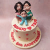 With a white base embellished with three dimensional hearts all over, this family cake features a figurine of a mother and father embracing each other and their toddler.