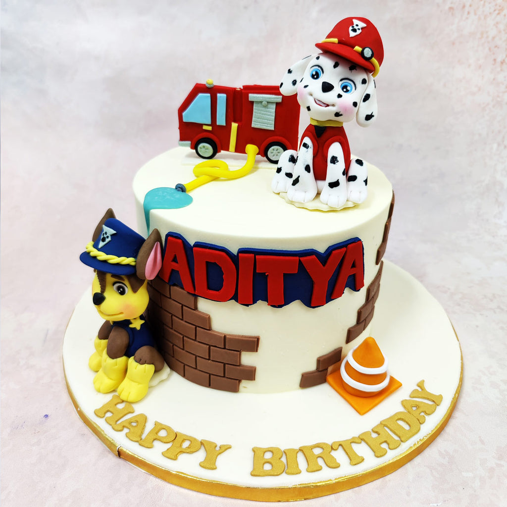 The Paw Patrol Firetruck Cake showcases impressive attention to detail with miniature accessories that bring the rescue theme to life—a tiny red fire engine, yellow fire hose, and orange traffic cone all contribute to the playful emergency services storyline. 
