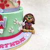 The bottom tier, featuring a vibrant mint green and pastel lavender base, showcases the iconic Paw Patrol badge front and centre, adorned with paw prints and a miniature dog collar detail, perfect for adding a touch of the series' canine charm to this Paw Patrol Zuma Cake. 