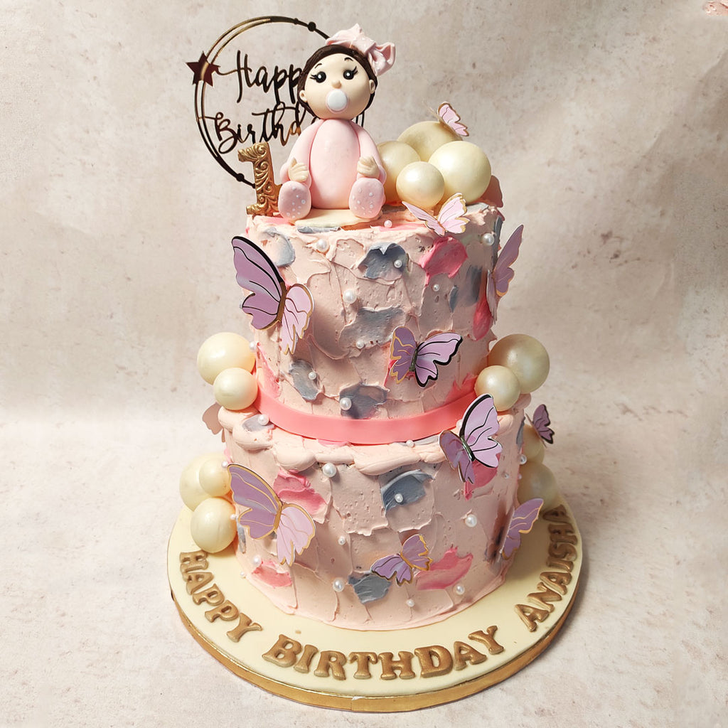 The two-tier pink buttercream butterfly cake with blue buttercream smears is a delightful creation that brings together the perfect combination of elegance and playfulness. 