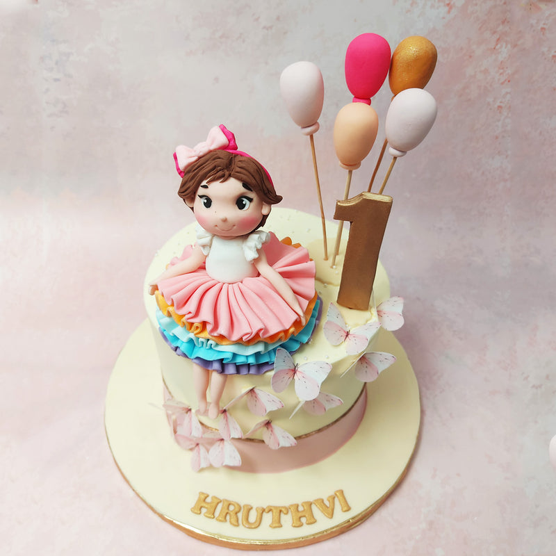 At the heart of this Colourful Butterfly Cake sits a charming figurine—a little girl with a frilly skirt.
