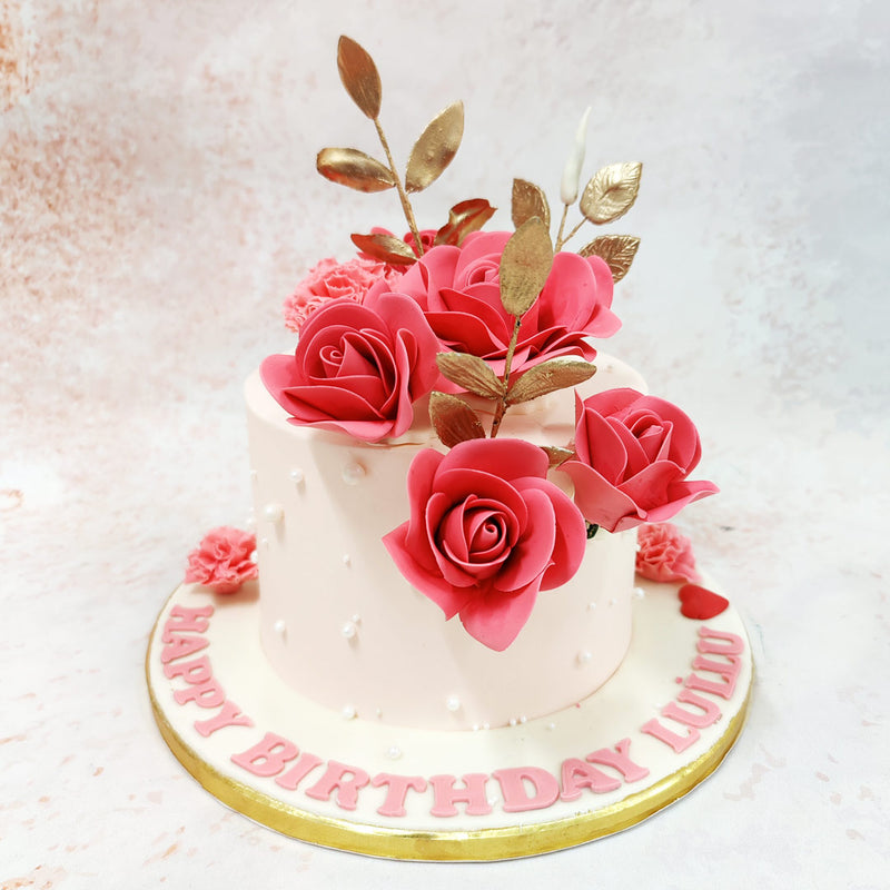 The smooth pale pink base serves as a perfect canvas for the exquisite floral arrangement that cascades across the top of this Pink Floral Cake. 