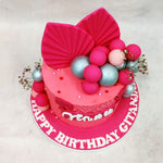The top of this Pink Leaf Cake is crowned with dramatic fan-textured chocolate sails in fuchsia, surrounded by glossy edible spheres in shades of hot pink, blush, and silver. Paired with clusters of baby’s breath and scattered pearls, the composition strikes a perfect balance between wild and refined.
