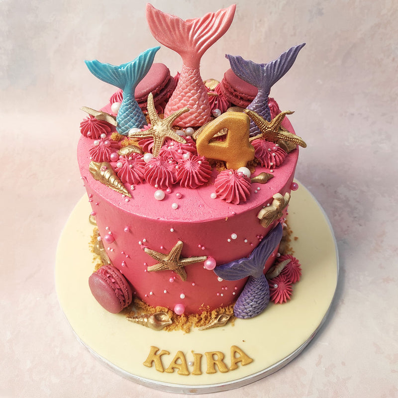 Adorning this Pink and Gold Mermaid Cake are shimmering gold seashells, starfish and iconic mermaid tails 