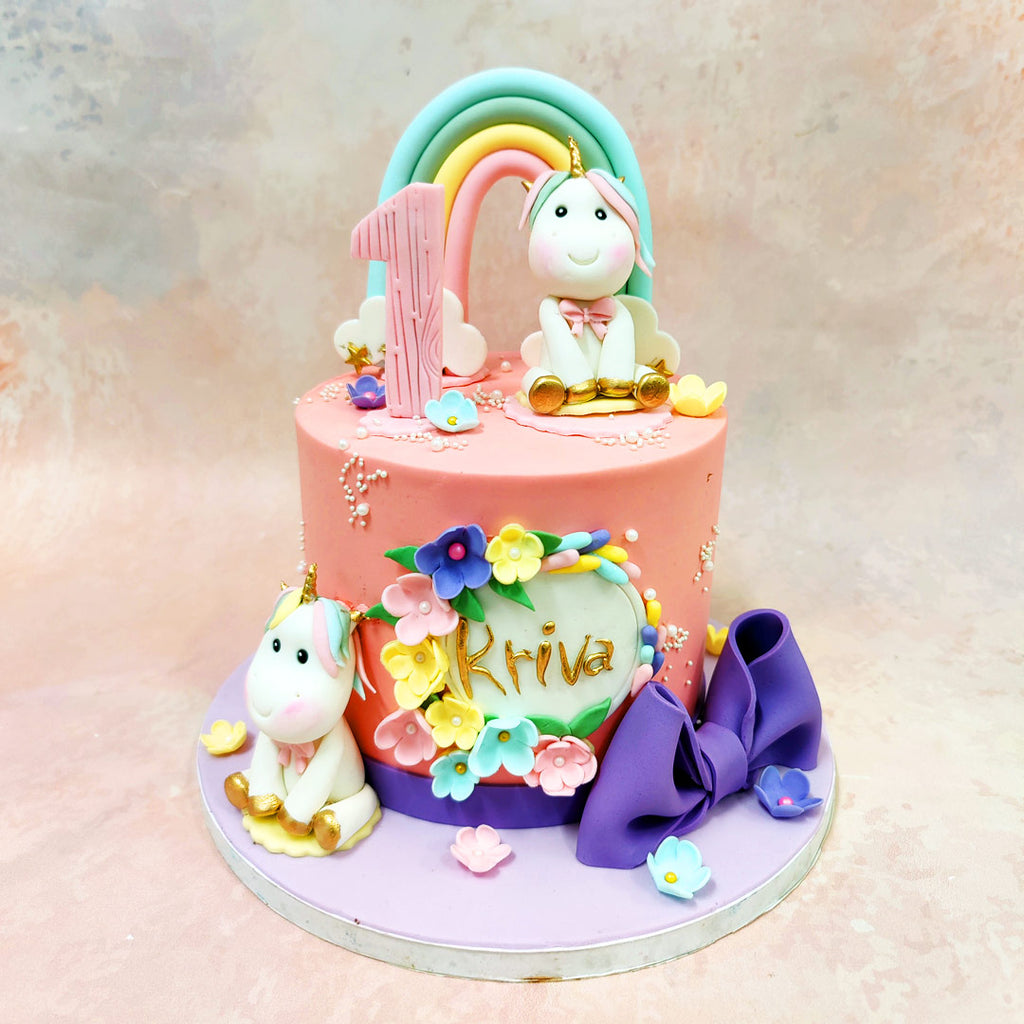 The centrepiece of this Pink Unicorn Cake With Rainbow features an adorable unicorn figurine sitting beneath a softly curved rainbow in gentle shades of mint, butter yellow, and blush pink. 