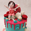 An array of decadent red and white macarons embellish this birthday cake for girls all over, further complemented by the figurine of a happy, little girl in a pink frock sitting on one on top.