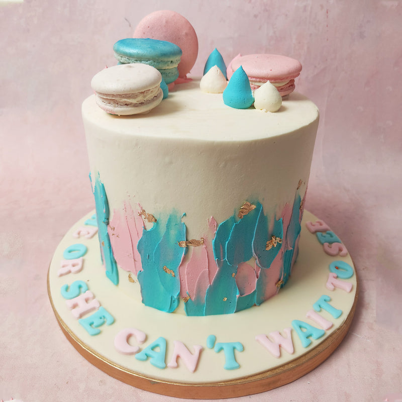 A sophisticated canvas of white, adorned with delicate light pink and light blue buttercream smears, creates an artistic symphony on this Babyshower Macaron Cake. 