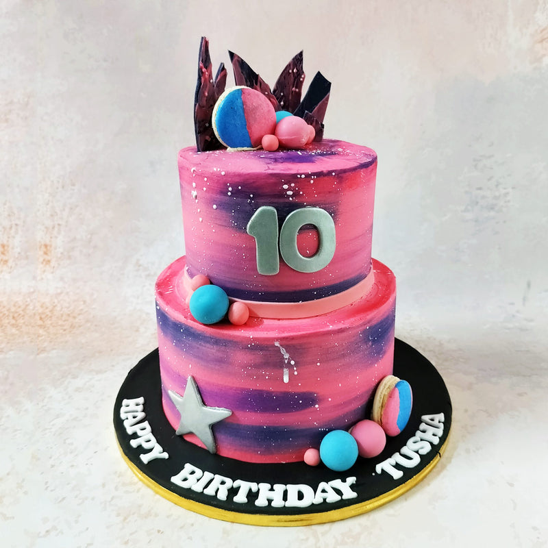 Embellishing this celestial Galaxy Ombre Cake are blue and pink macaroons and chocolate balls, mirroring the cosmic palette. 