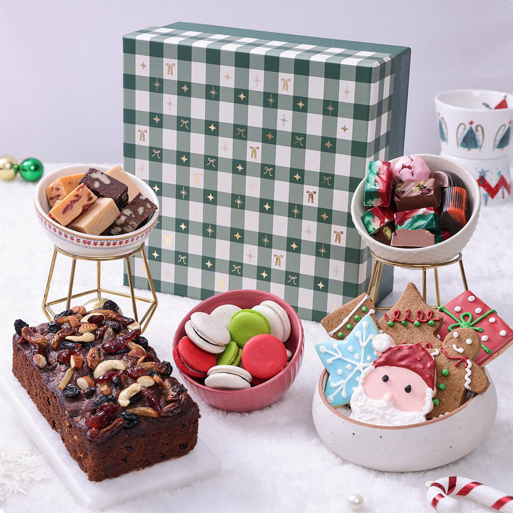 Luxury Premium Christmas Gift Basket in green plaid box, featuring plum cake, assorted fudge, Christmas macarons, assorted chocolates, and decorated sugar cookies.