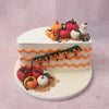 These edible figurines playfully gather at both the bottom and the top of this Fall Theme Half Birthday Cake on a biscuit crumb base.