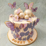 This purple butterfly cake features a luscious cream base, adorned with delightful purple buttercream smudges that add a touch of whimsy. 
