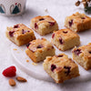 Assorted Raspberry Almond Financier squares topped with slivered almonds and fresh raspberries, set for Christmas.