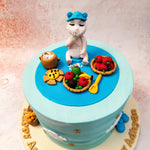 This Rice Ceremony Cake is adorned with a serene sky-blue background, symbolising purity and new beginnings. 