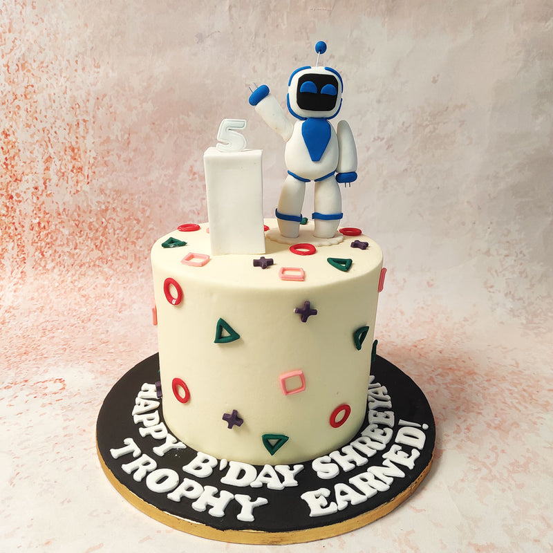 This Robot Theme Cake's surface is adorned with colourful shapes that echo familiar icons from the gaming world. 