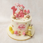 At the top of this teddy bear cake sits an adorable teddy wearing a pink frock and matching bow, holding balloons in its hand. 