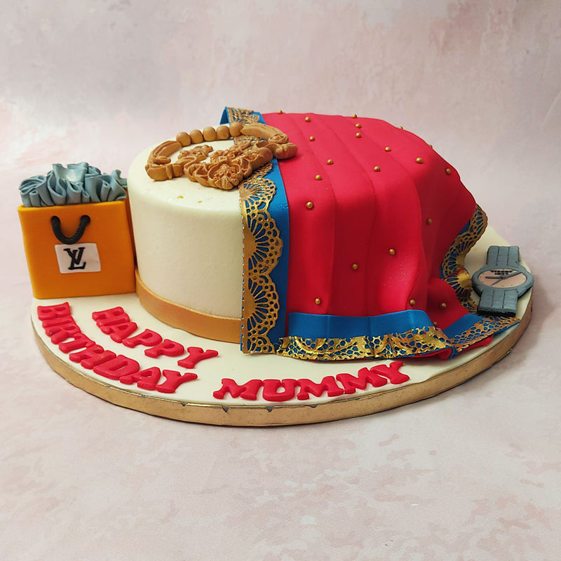 Spot at the bottom of this saree cake design, the aesthetic elements that complement this look, from the jewellery carefully laid on top to the watch at the side. 