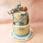 Picture this: a pristine white sea themed cake that serves as a canvas adorned with vibrant blue waves at the bottom, creating the illusion of an endless ocean. The waves gently lap against the sides of this aquatic cake, inviting young explorers to embark on an exciting journey beneath the sea.